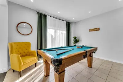 a room with a pool table and a yellow chair at Oshawa Family Haven - Luxury 7BR Villa with Cozy Fireplaces & Hot Tub in Oshawa