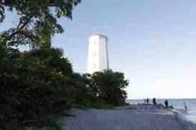 a lighthouse on the shore of a beach at The Barns of Brighton Near Prince Edward County in Brighton