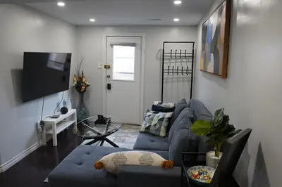 a living room with a blue couch and a tv at Patio privé, hébergement équipé et spacieux. in Hamilton