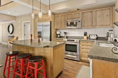a kitchen with wooden cabinets and red bar stools at Lakeside at Rocky Crest Resort and Golf Club on Joseph Lake in Rosseau