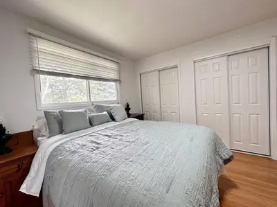 a white bedroom with a large bed and a window at Cozie cottage at Niagara-On-The-Lake in Queenston
