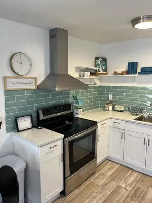 a kitchen with white cabinets and a clock on the wall at Casa Di Nonna in Wasaga Beach
