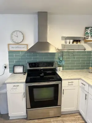 a kitchen with a stove and a clock on the wall at Casa Di Nonna in Wasaga Beach