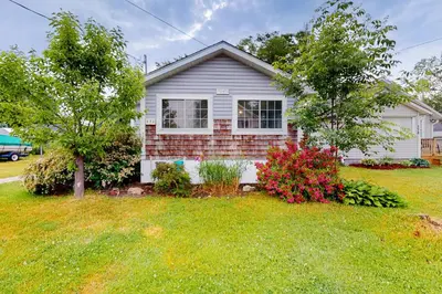 a white house with a yard with trees and flowers at Mary Jane's Cottage in Crystal Beach
