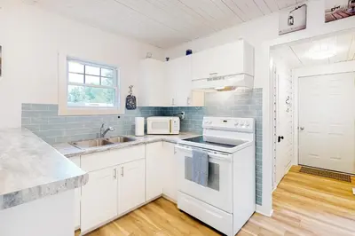 a white kitchen with a sink and a stove at Mary Jane's Cottage in Crystal Beach