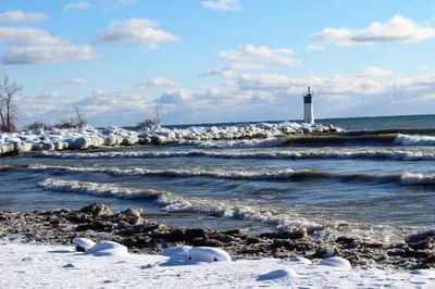 a lighthouse in the ocean with snow on the shore at The Birch in Wellington