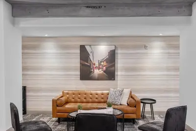 a living room with a brown leather couch and chairs at Cannery Lofts Niagara in Niagara Falls