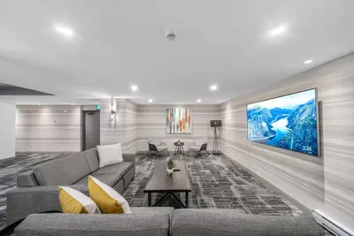 a living room with a couch and a tv on a wall at Cannery Lofts Niagara in Niagara Falls