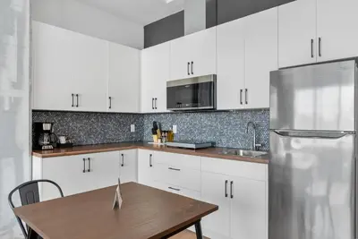 a kitchen with white cabinets and a table and a refrigerator at Cannery Lofts Niagara in Niagara Falls