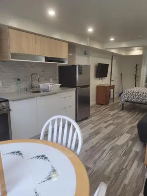 a kitchen and living room with a table and a couch at Modern studio with kitchenette and bath in Guelph