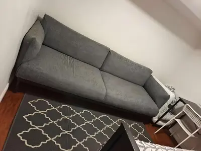 a gray couch in a living room with a rug at BASEMEWNT Room with private bathroom 36C in Toronto