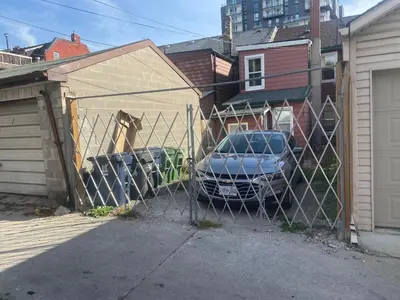 a fence with a car parked in a garage at BUDGET Triple Room with En Suite Bathroom 36A in Toronto
