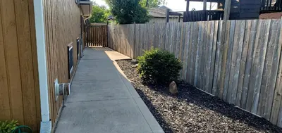 a cat sitting on a sidewalk next to a fence at Spacious Guest Suite in Hamilton