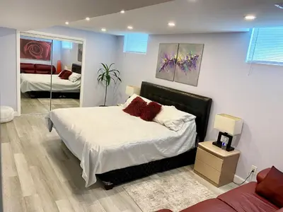 a bedroom with a large bed and a mirror at Gilford Beach Apartment in Innisfil