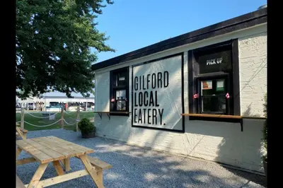 a wooden picnic table in front of a building at Gilford Beach Apartment in Innisfil