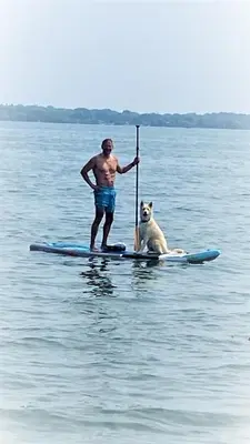 a man and a dog on a paddle board in the water at Gilford Beach Apartment in Innisfil
