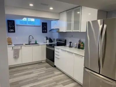 a kitchen with white cabinets and a stainless steel refrigerator at Gilford Beach Apartment in Innisfil