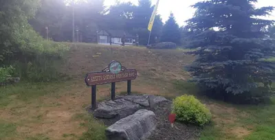 a sign in a field with a house in the background at Burnt River Bungalow in Kinmount