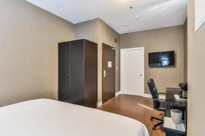 a bedroom with a bed and a desk and a tv at NU Hotel Toronto Airport in Mississauga
