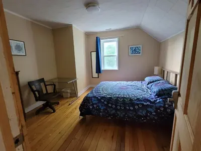 a bedroom with a bed and a desk and a window at 23Maple in Haliburton