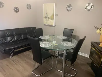 a dining room with a glass table and black chairs at Lovely apartment house in Grimsby
