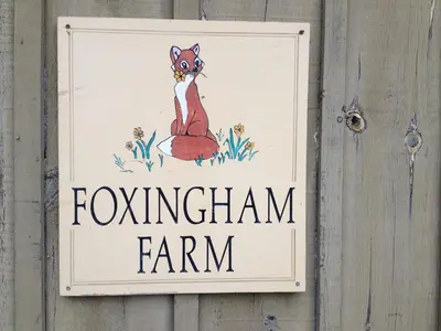 a sign on a wooden fence with a foxgan farm at Foxingham Farm Bed & Breakfast in Mulmur