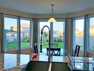 a dining room with a table and chairs and windows at Home Pearl B&B in Niagara Falls