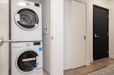 a laundry room with a washer and dryer next to a door at 2 Bedroom, 2 Bath Stunning Condo - heart of Kitchener Downtown in Kitchener