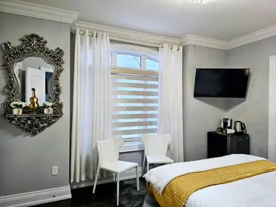 a bedroom with a bed and two chairs and a mirror at Lilen's Home in Toronto