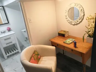 a living room with a chair and a table and a mirror at Margie Townhome Suites in Toronto