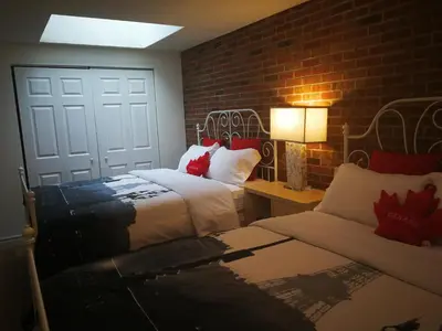 a bedroom with two beds and a brick wall at Margie Townhome Suites in Toronto