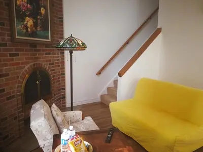a living room with a yellow couch and a fireplace at Margie Townhome Suites in Toronto