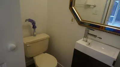 a bathroom with a toilet and a sink and a mirror at Margie Townhome Suites in Toronto
