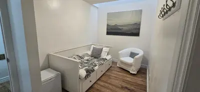 a white nursery with a crib and a chair at Margie Townhome Suites in Toronto