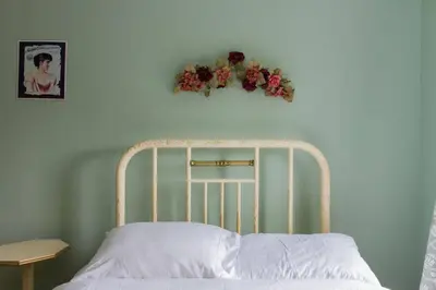 a white bed with a flower wreath on the wall at Wine Country 4 bedrooms in Wellington