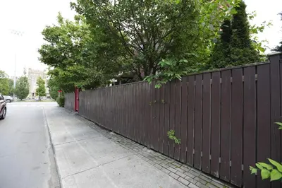 a fence on the side of a sidewalk next to a street at Phoebe Wang in Toronto