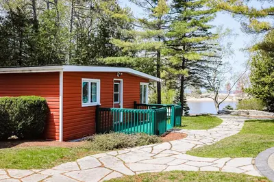 a small red house with a green fence at Fiddlers Green Cottage Two in Wasaga Beach
