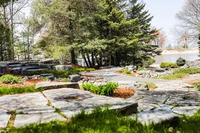 a garden with rocks and trees and a body of water at Fiddlers Green Cottage Two in Wasaga Beach