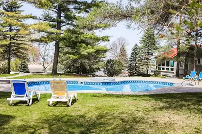two chairs in the grass next to a swimming pool at Fiddlers Green Cottage Two in Wasaga Beach