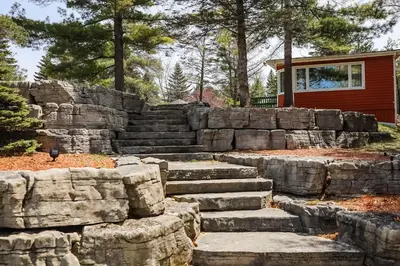 a stone retaining wall with stairs in front of a house at Fiddlers Green Cottage Two in Wasaga Beach