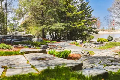 a garden with rocks and trees and a body of water at The Gardenhouse Cottage One in Wasaga Beach