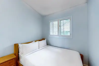 a white bedroom with a bed and a window at The Gardenhouse Cottage One in Wasaga Beach