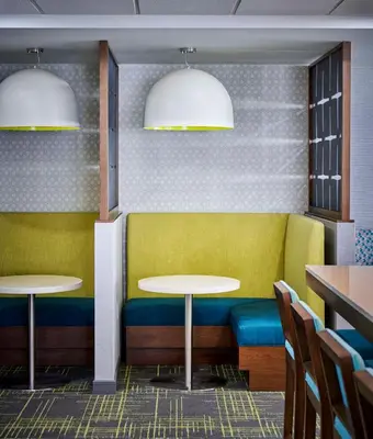 a restaurant with yellow and blue seats and tables at Hampton Inn By Hilton Hamilton in Hamilton