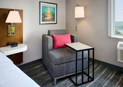 a room with a chair and a table and a bed at Hampton Inn By Hilton Hamilton in Hamilton
