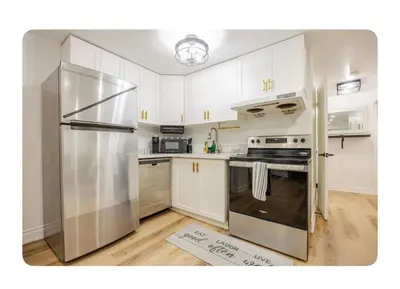 a kitchen with white cabinets and a stainless steel refrigerator at LUXURIOUS 1000 SQ FT Oasis in Brampton
