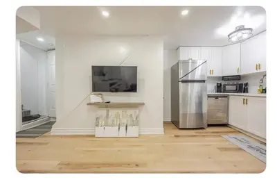 a kitchen with white cabinets and a stainless steel refrigerator at LUXURIOUS 1000 SQ FT Oasis in Brampton