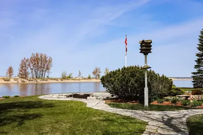 a flag pole with a stone walkway next to a river at The Dockhouse Cottage Five in Wasaga Beach
