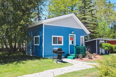 a blue tiny house with a grill in a yard at The Lighthouse Cottage Four in Wasaga Beach