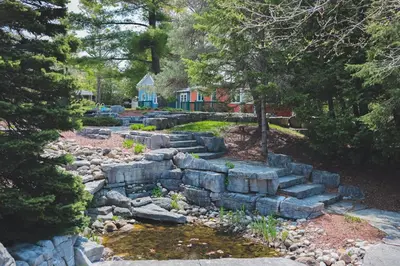 a rock garden with a pond and a house at The Lighthouse Cottage Four in Wasaga Beach