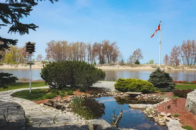 a garden with a pond in front of a river at The Lighthouse Cottage Four in Wasaga Beach